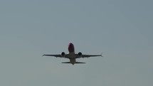A frontal long distance shot of a plane taking off from the airport with mountains background