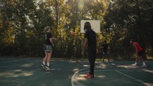 Young men playing basketball on an outdoor court on a sunny day