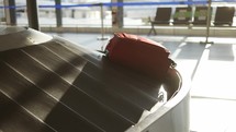 Close up of a red suitcase moving in the conveyor belt of terminal airport.