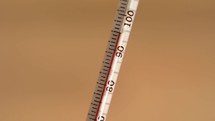 Close up of a thermometer rising to over 100 degrees