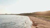 Sunset Serenity: Aerial View Over Beach with Waves Washing Ashore