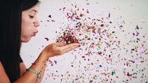 a woman blowing confetti out of her hands 