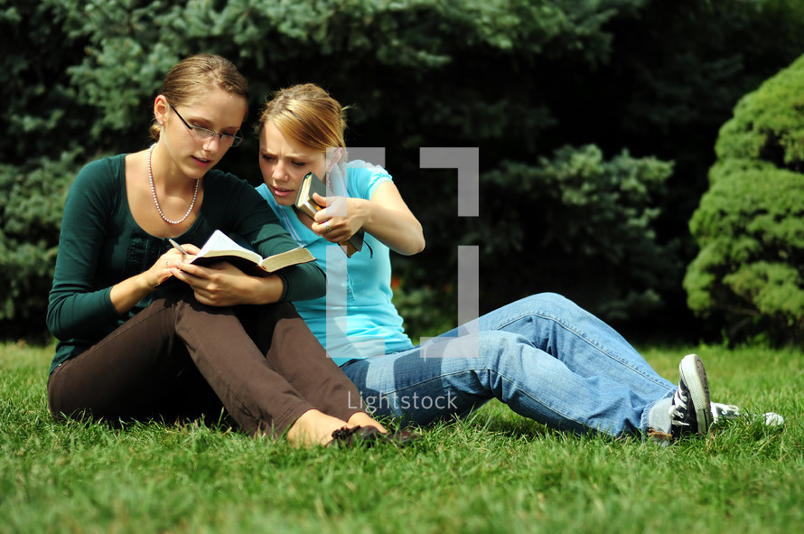 teen girls reading a Bible outdoors 