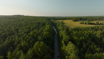 Car Driving Down Empty Rural Road in the Country at Sunset. Aerial footage following car driving on a country road in Mississippi.