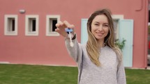 Satisfied lady showing keys of new apartment outside new home.