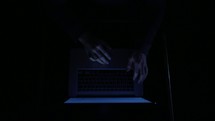 hands on a laptop computer in darkness 