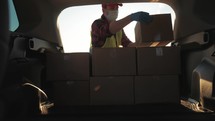 Delivery driver loading his van with boxes. Professional mover loads it cardboard boxes in car. Goods transportation and shipping.