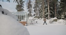 a woman carrying plants in to a greenhouse in the snow 