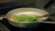 Cooking Green Pesto Tagliatelle Pasta In The Pan Of A Restaurant