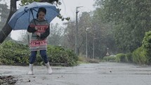 Slow motion of a little girl skipping in puddles holding an umbrella in the rain