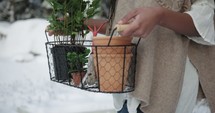 a woman walking through the snow carrying plants 