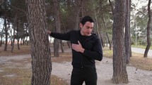 Man Does Stretching Chest In The Pine Forest In A Park