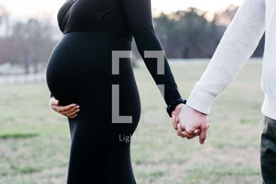 expecting couple holding hands 