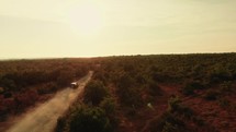 Drone following a car at sunset on small and dusty road