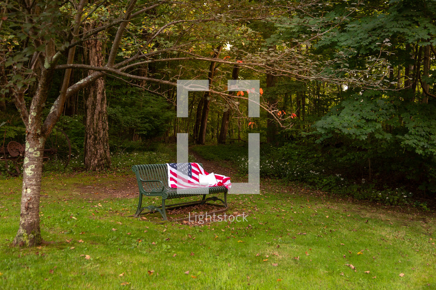 American flag and Bible on bench in park in evening