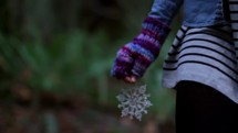 woman walking outdoors holding a snowflake ornament 