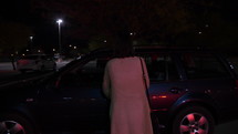 A woman walking to her car in a parking lot at night