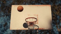 Close up of a basketball being shot on an outdoor basketball court on a sunny day