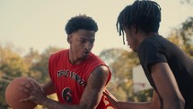 Young men playing basketball on an outdoor court on a sunny day