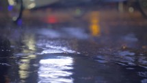 Drizzle and puddles on the asphalt with lights reflection