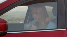 Woman waiting in car with a hot drink