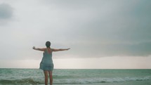 woman standing in the ocean with outstretched arms 