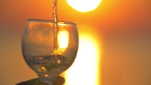 Pouring water into glass at sunset