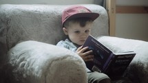 toddler boy sitting reading books 
