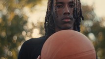 Portrait of a smiling young man playing basketball on a sunny day