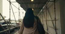 Young business woman walking around the city using her phone and laptop