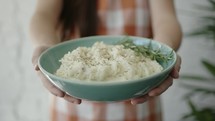 a woman holding a bowl of mashed potatoes