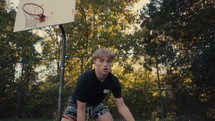 Young man dribbling a basketball on an outdoor court on a sunny day