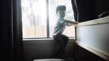 toddler sitting in a window 