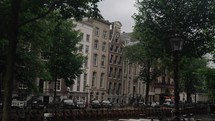 Typical Dutch Narrow Buildings By The Canal River In Amsterdam, Holland, Netherlands, Europe. Handheld Shot