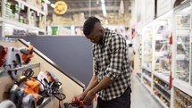 African american buyer selecting tool in building and repair shop indoors.