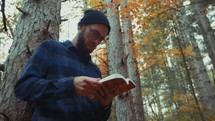 a man reading a Bible in the woods in fall 