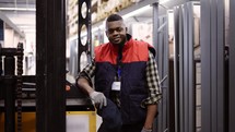 Close up portrait of forklift operator in the warehouse, wearing uniform and badge.