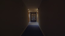 Guik quickly walks down the corridor of the hotel with yellow doors with room numbers