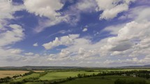 Drone forward motion over verdant fields under blue sky