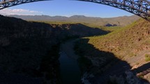 Aerial reveal of an arched bridge over a rugged canyon