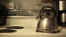 Steaming kettle boiling on a stove top.