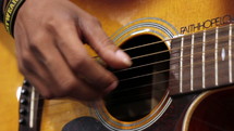 Hands strumming an acoustical guitar.