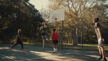 Young men playing basketball on an outdoor court on a sunny day