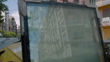 The reflection of a residential house on the glass of an old window, standing next to a trash container, Spain, Valencia