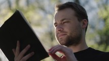 Young man reading his Bible outside on a warm sunny day