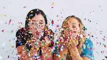 women blowing confetti 