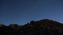 Timelapse of stars rising over a rocky hill in the desert