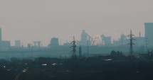 Air Pollution In Galati City From Chimney Stack Of Industrial Factory With Transmission Towers In Foreground.