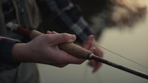 Young fly fisherman casting on a foggy river at sunrise