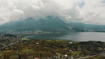 Imbabura Volcano In Clouds With San Pablo Lake In Foreground In Rural Town Of Otavalo In Ecuador. wide aerial drone